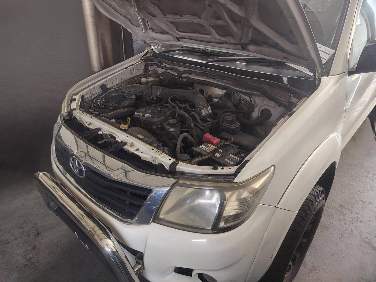 Engine bay of a white Toyota Hilux open for inspection at H2 Service Centre.